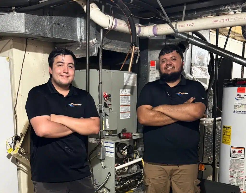 Two SwiftPro technicians beside heating and water-heating equipment
